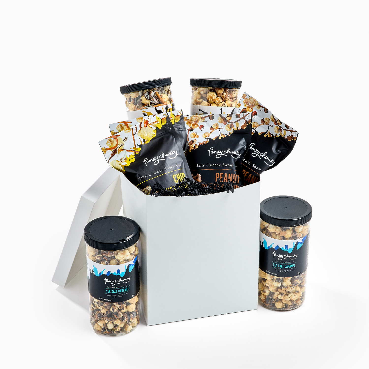 A white gift box filled with Funky Chunky Gourmet Popcorn Flavors - Sea Salt Caramel, Peanut Butter Cup and Chip Zel Pop including bags of candy corn and peanut butter popcorn, and two jars of popcorn on a clean white background.